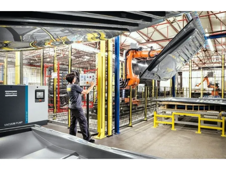 Vakuumanlegg fra Atlas Copco i en produksjonshall med industrirobot